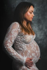 Femme enceinte en shooting photo studio avec une robe blanche