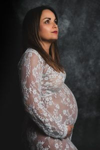 Femme enceinte en shooting photo studio avec une robe blanche